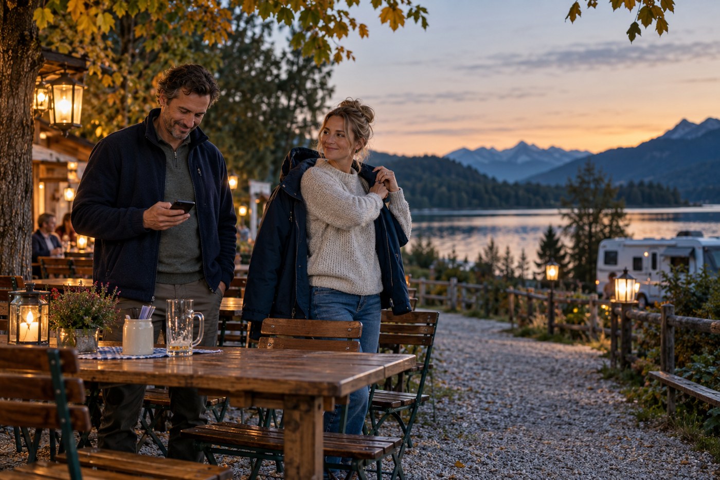 Ein Paar zieht im abendlichen Biergarten die Jacken an und nutzt vor dem Heimweg kurz das Smartphone